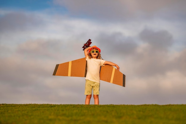 Niño pequeño está jugando y soñando con volar sobre las nubes Concepto de infancia Niño lindo jugando con las alas de un avión de juguete