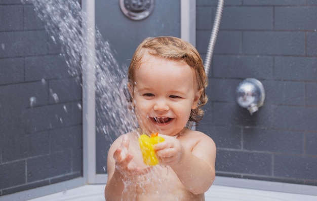 Niño pequeño se está lavando el pelo en el baño niño en la ducha