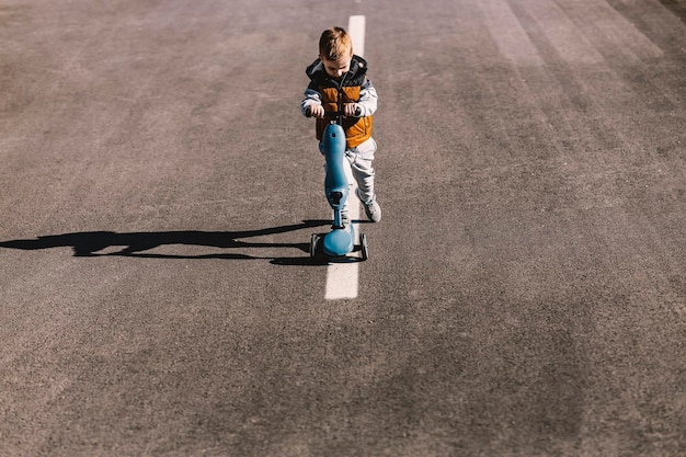 Un niño pequeño está montando scooter en la calle del centro