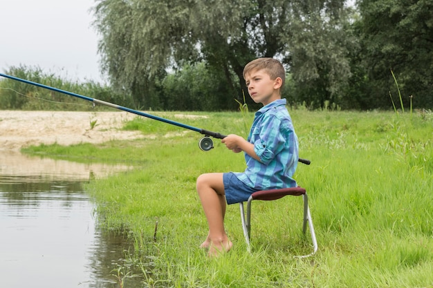 Niño pequeño está pescando en el río