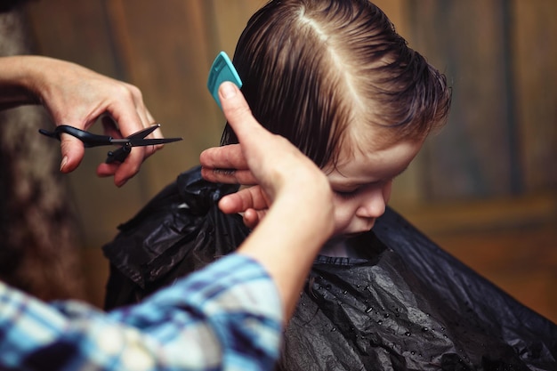 Un niño pequeño está recortado en las brillantes emociones del peluquero en su rostro.