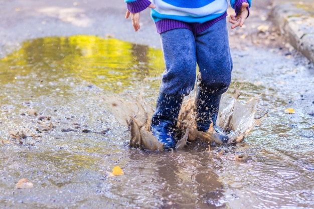 Un niño pequeño está saltando en un charco.