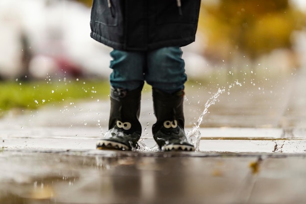 Un niño pequeño está saltando en el estanque en la calle de la ciudad