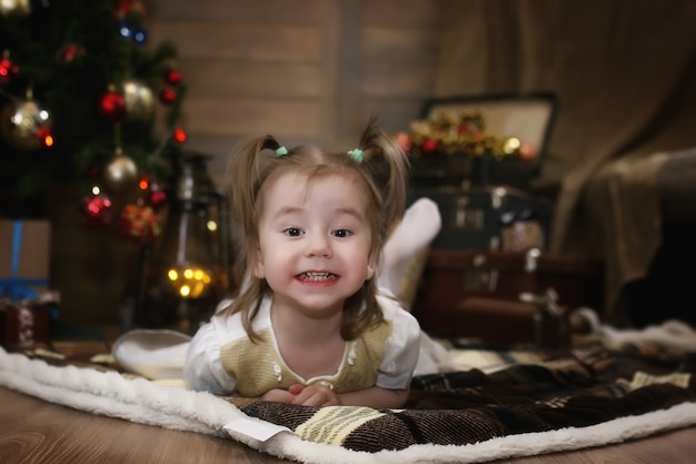 Un niño pequeño está sentado con un abeto con adornos navideños