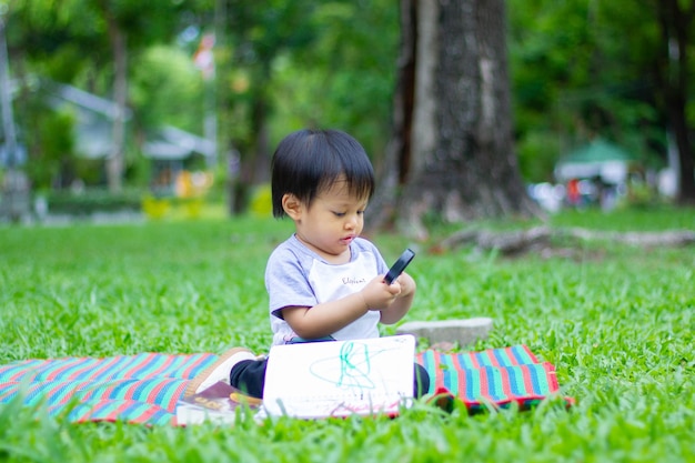 El niño pequeño está sentado en una alfombra en un parque natural verde ternura en movimiento natural