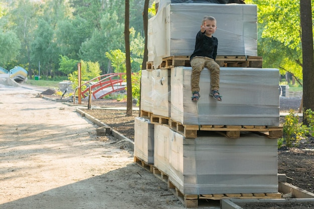 Un niño pequeño está sentado sobre materiales de construcción El concepto de juegos de seguridad infantil en los lugares equivocados descuido