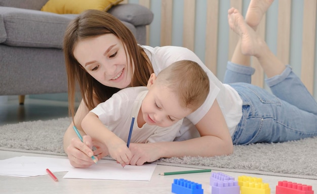 Niño pequeño feliz dibujando a mano con mamá