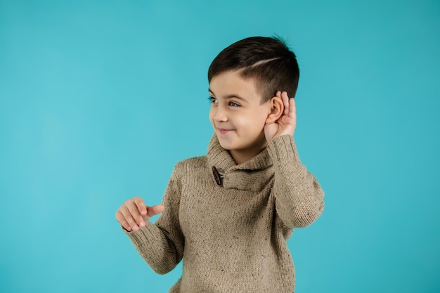 Foto niño pequeño feliz haciendo gesto auditivo