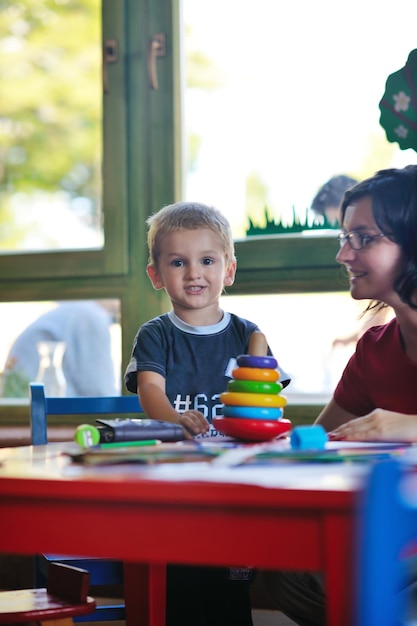 niño pequeño feliz juega y diviértete, lecciones de educación en el colorido parque infantil en el interior