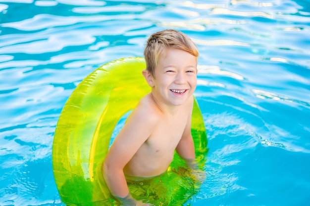 Niño pequeño feliz nada en la piscina en un círculo inflable de goma en verano verano niños fin de semana niños vacaciones niño en el parque acuático