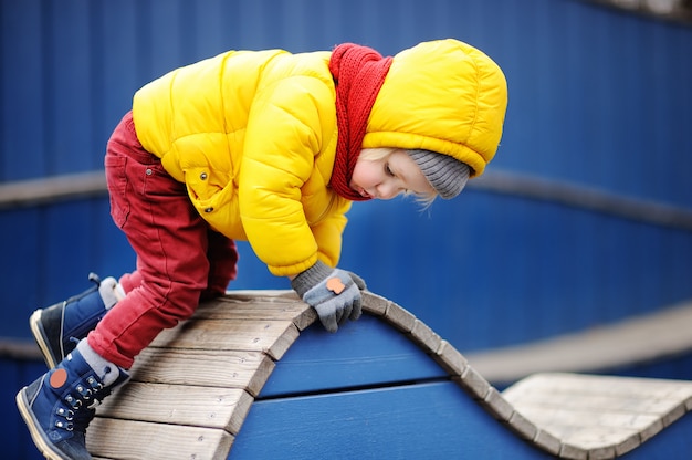 Niño pequeño feliz que se divierte en patio al aire libre. Primavera y otoño ocio activo para niños.