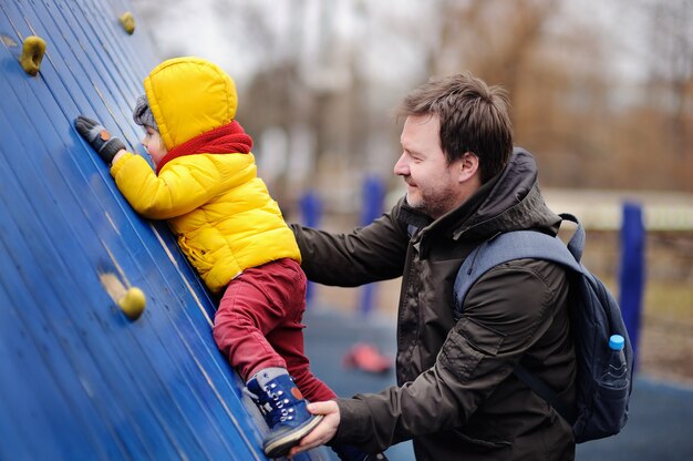 Niño pequeño feliz con su padre que se divierte en patio al aire libre. Primavera y otoño ocio activo para niños.