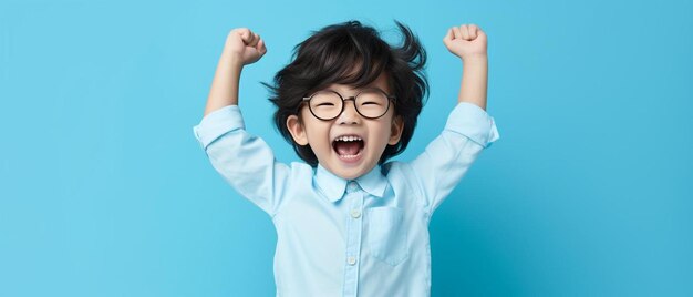 un niño pequeño con gafas y levantando los brazos en el aire