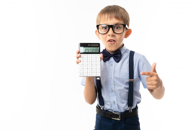 Niño pequeño con gafas negras con gafas transparentes, camisa azul, pull-ups, pantalones azules se muestra en la calculadora