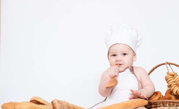 Niño pequeño con gorra de cocinero y con pan pequeño chef divertido