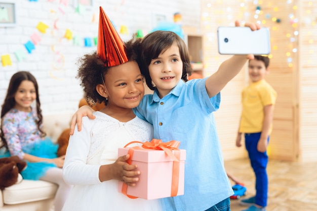 El niño pequeño hace selfie con la niña feliz cumpleaños