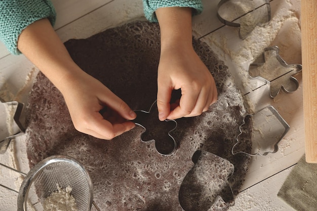 Foto niño pequeño haciendo galletas de navidad en la vista superior de la mesa de madera blanca