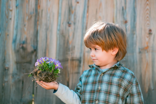 Niño pequeño haciendo jardinería y divirtiéndose en el jardín de primavera