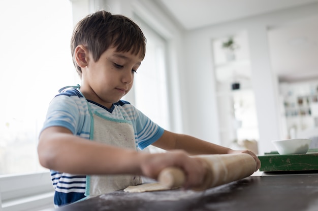 Niño pequeño haciendo masa para delicioso dulce