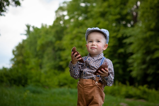 Niño pequeño con un huevo de chocolate grande en la naturaleza