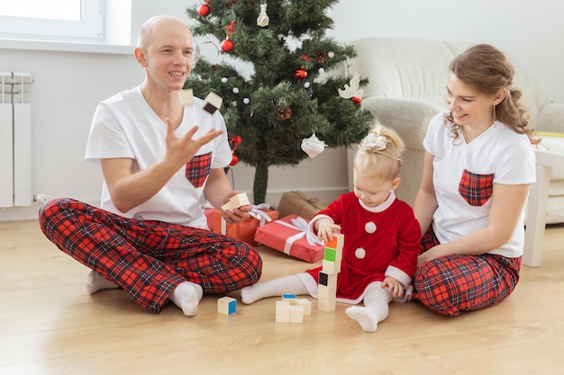 Niño pequeño con implante coclear juega con los padres bajo la sordera del árbol de navidad e innovando tecnologías médicas para audífonos y diversidad