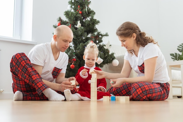 Niño pequeño con implante coclear juega con los padres bajo la sordera del árbol de navidad e innovando tecnologías médicas para audífonos