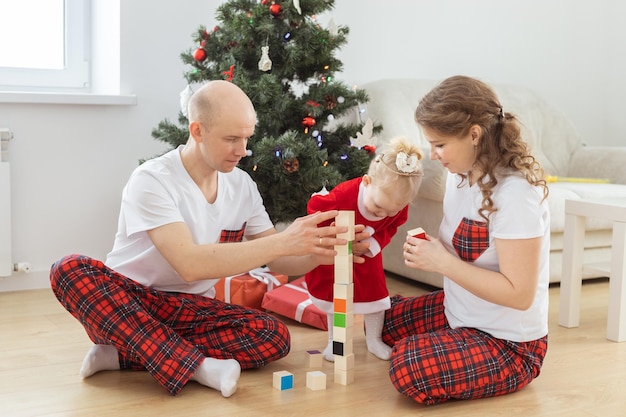 Niño pequeño con implante coclear juega con los padres bajo la sordera del árbol de navidad e innovando