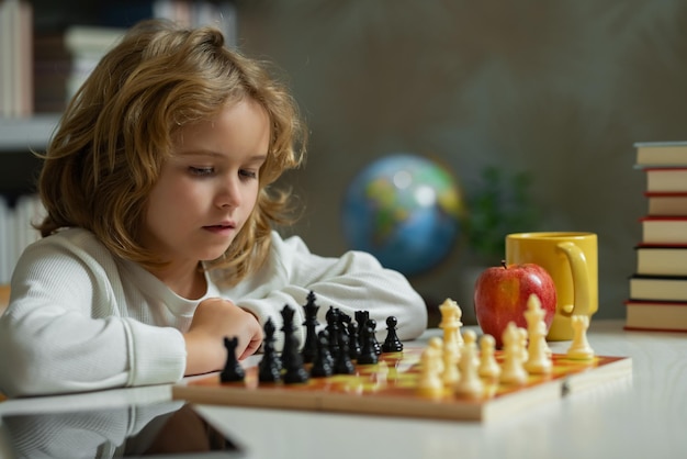 Niño pequeño juega al ajedrez en la clase de la escuela Niño jugando al juego de mesa Lluvia de ideas e ideas del niño pensante en el juego de ajedrez Escuela de ajedrez y concepto de educación infantil Desarrollo cerebral y lógica