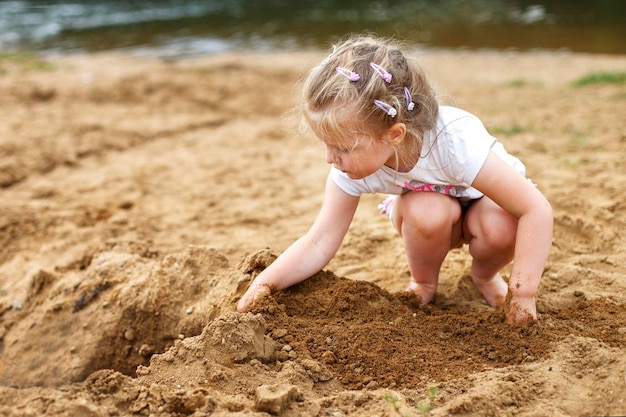 Un niño pequeño juega con la arena Hermosa niña sentada en la playa