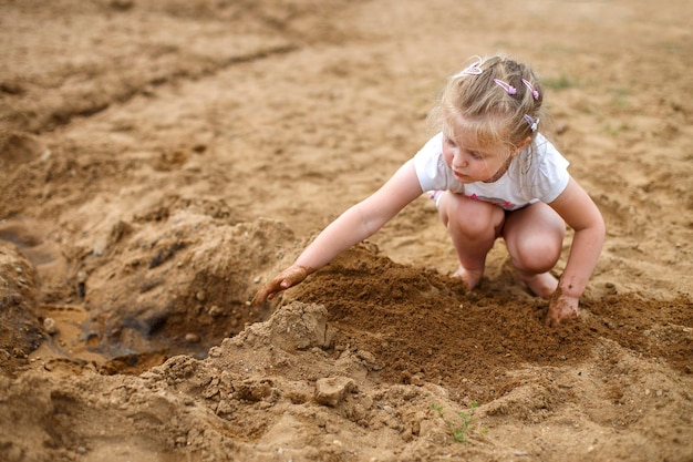 Un niño pequeño juega en la arena Hermosa niña sentada en la playa