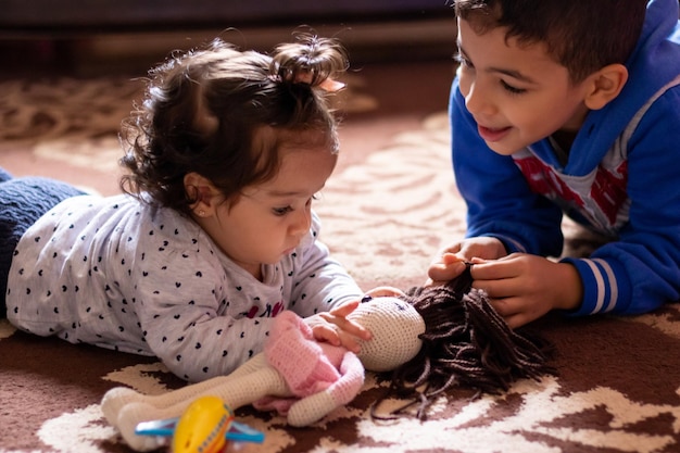 Un niño pequeño juega con una muñeca en el suelo.