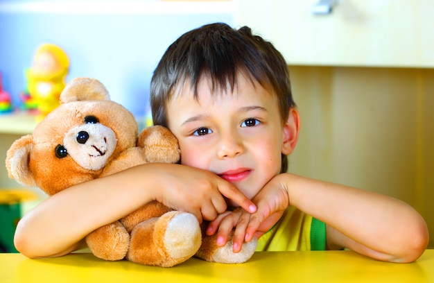 Niño pequeño juega con un oso de peluche