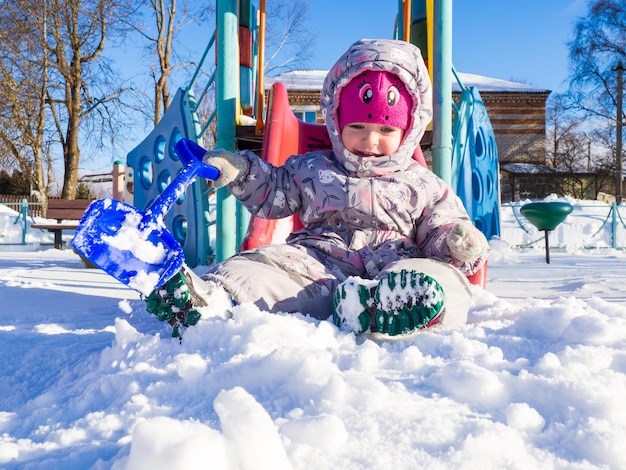 Un niño pequeño juega en el patio de recreo con nieve.