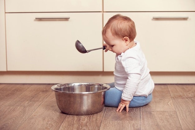 Un niño pequeño juega en el piso de la cocina.