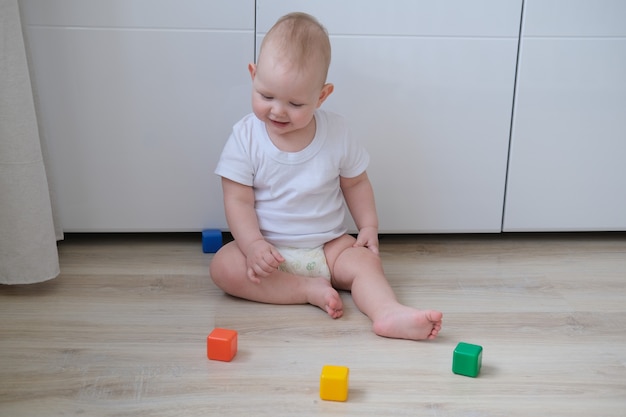 Un niño pequeño juega en el suelo con cubos de colores y construye una pirámide con ellos.