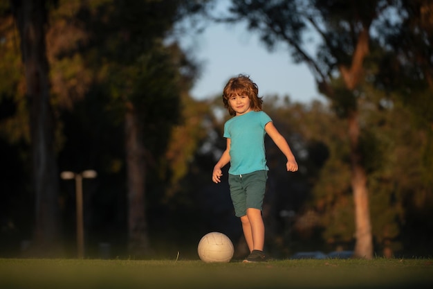 Niño pequeño jugando al fútbol en el campo con el concepto de pelota de fútbol de los niños deporte niño jugando