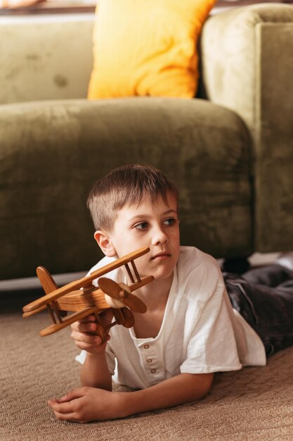 Niño pequeño jugando con un avión de madera de juguete en el interior