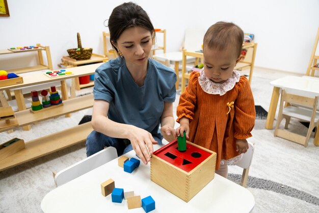 Niño pequeño jugando con la caja de formas montessori Imbucare