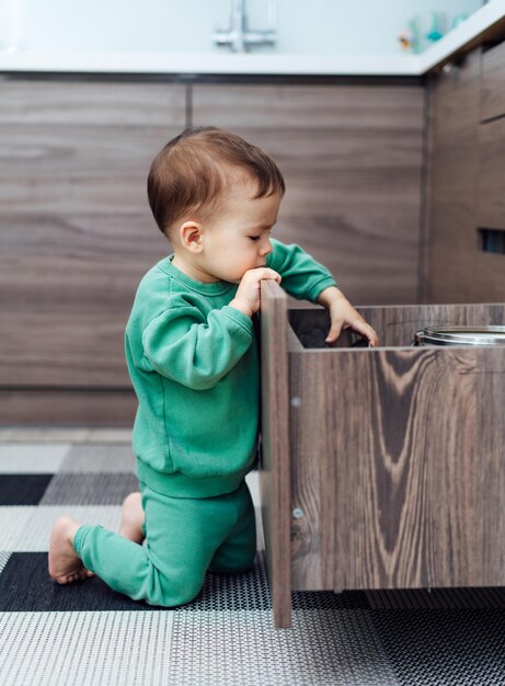 Niño pequeño jugando con cajón Bebé solo en la cocina Seguridad del bebé en la cocina