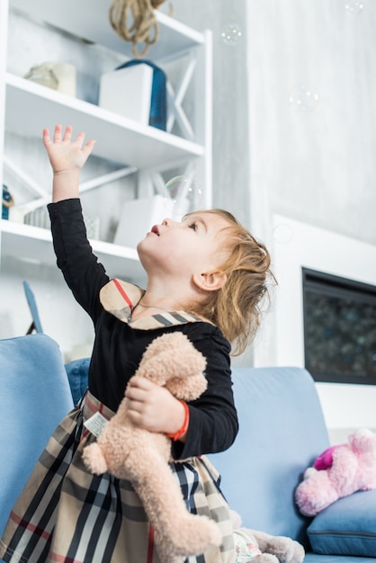 Niño pequeño jugando en casa con pompas de jabón