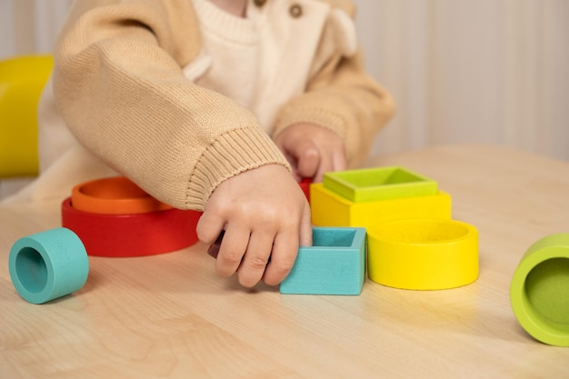 Niño pequeño jugando con juguetes Montessori de madera multicolores Manos de primer plano