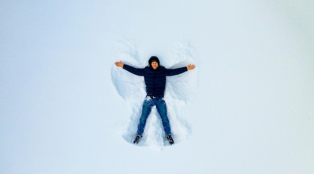Foto un niño pequeño jugando en la nieve haciendo un ángulo niño juega en la nieve blanca vista desde arriba