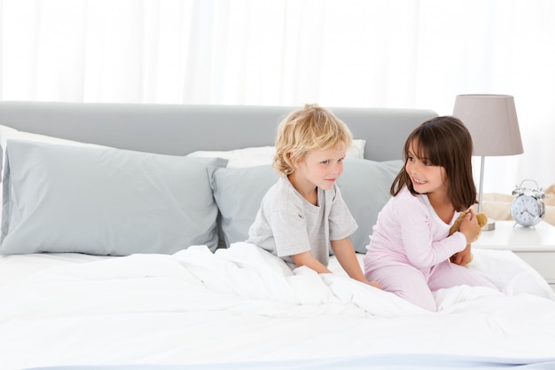 Niño pequeño jugando con su hermana en la cama de sus padres