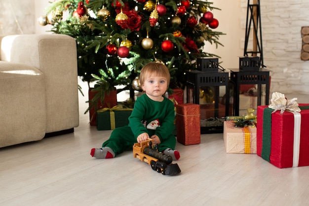 Niño pequeño jugando con tren de juguete, árbol de Navidad