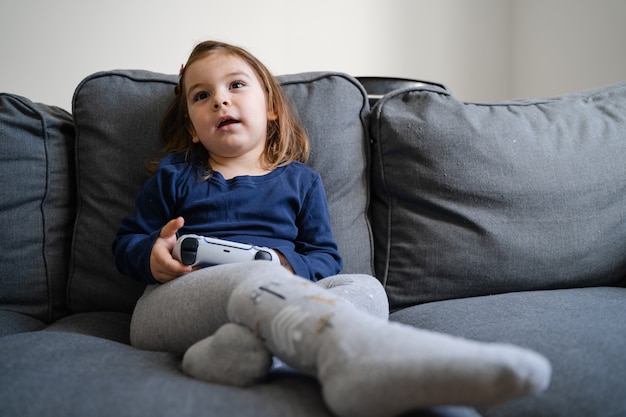 Niño pequeño jugando videojuegos con gamepad en la consola