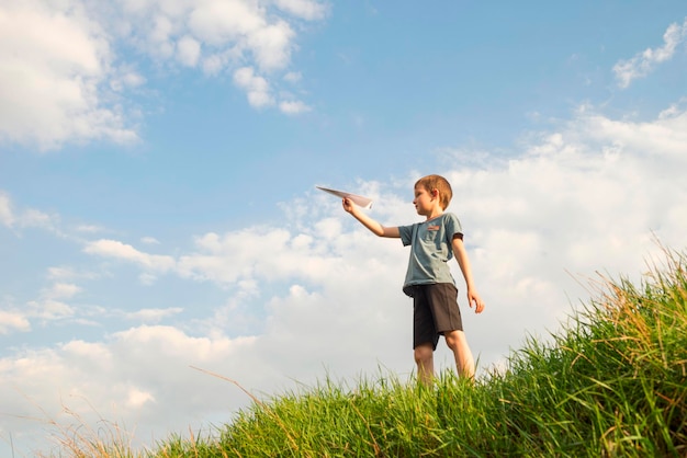Un niño pequeño lanza un avión de papel en el aire un niño lanza un aeroplano de papel