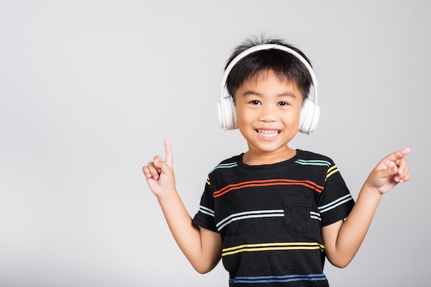 Un niño pequeño y lindo de 5 años escucha música con auriculares inalámbricos