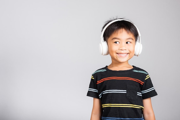 Un niño pequeño y lindo de 5 años escucha música con auriculares inalámbricos