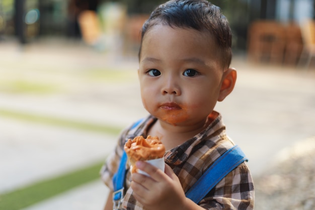 Niño pequeño lindo asiático que come el helado