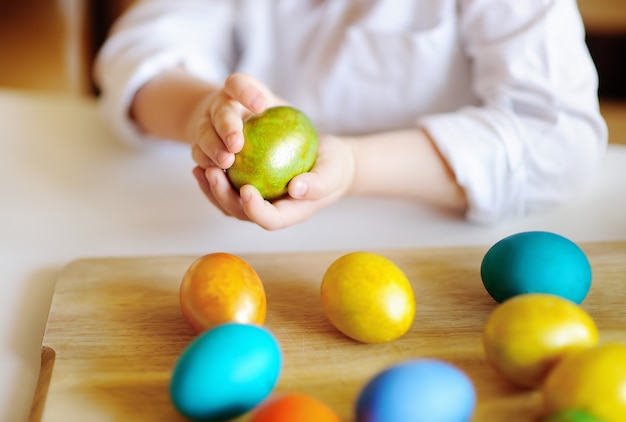 Niño pequeño lindo cazando huevos de Pascua el día de Pascua